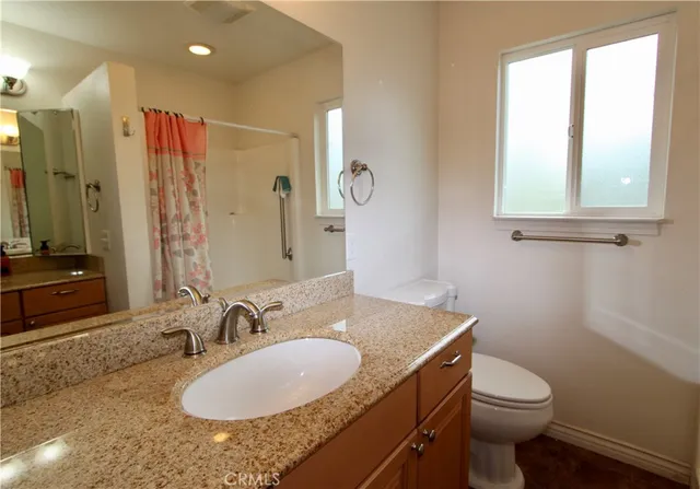 a bathroom with a granite countertop sink toilet and a mirror