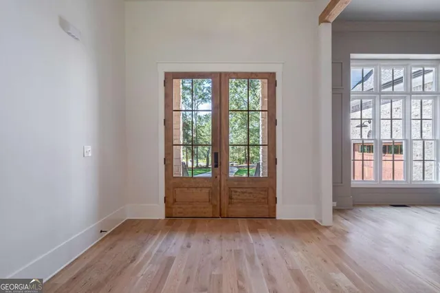 a view of an empty room with wooden floor and a window