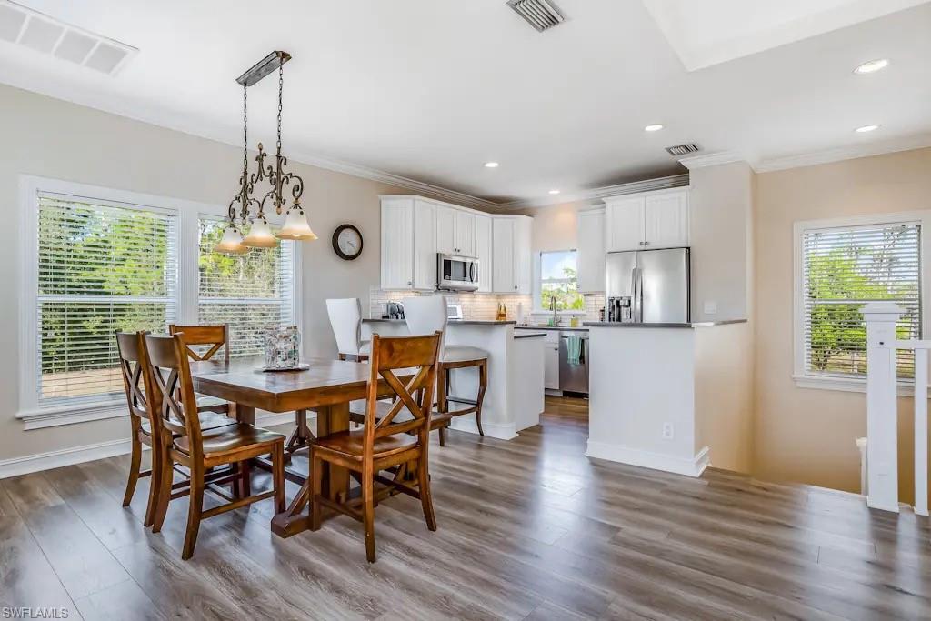 6941 Hunters Road Naples, FL 34109 - Photo 11 of 48 a view of a dining room and livingroom with furniture wooden floor a chandelier