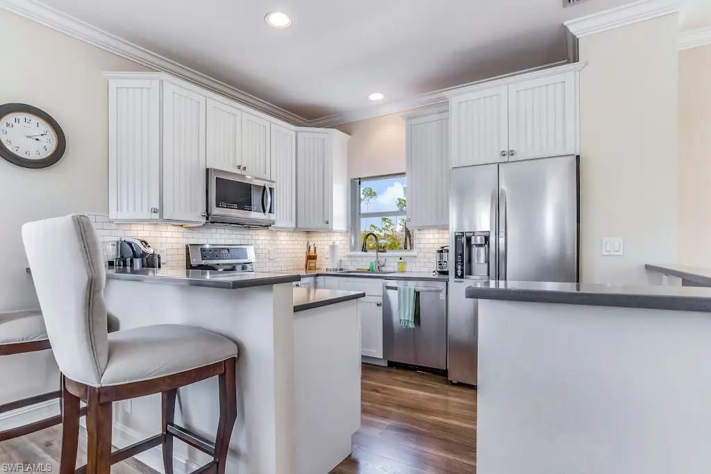 6941 Hunters Road Naples, FL 34109 - Photo 12 of 48 a kitchen with stainless steel appliances granite countertop a table chairs microwave and refrigerator