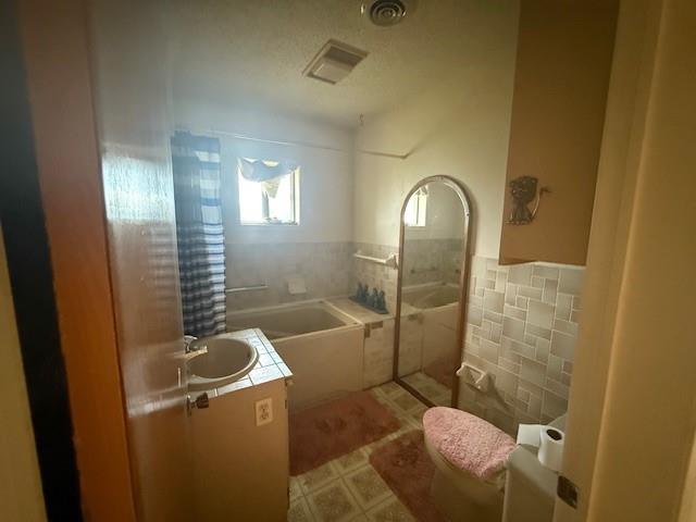 909 Railroad Street Rochester, TX 79544 - Photo 11 of 19 Full bath with tile walls, vanity, a bath, tile patterned floors, and wainscoting