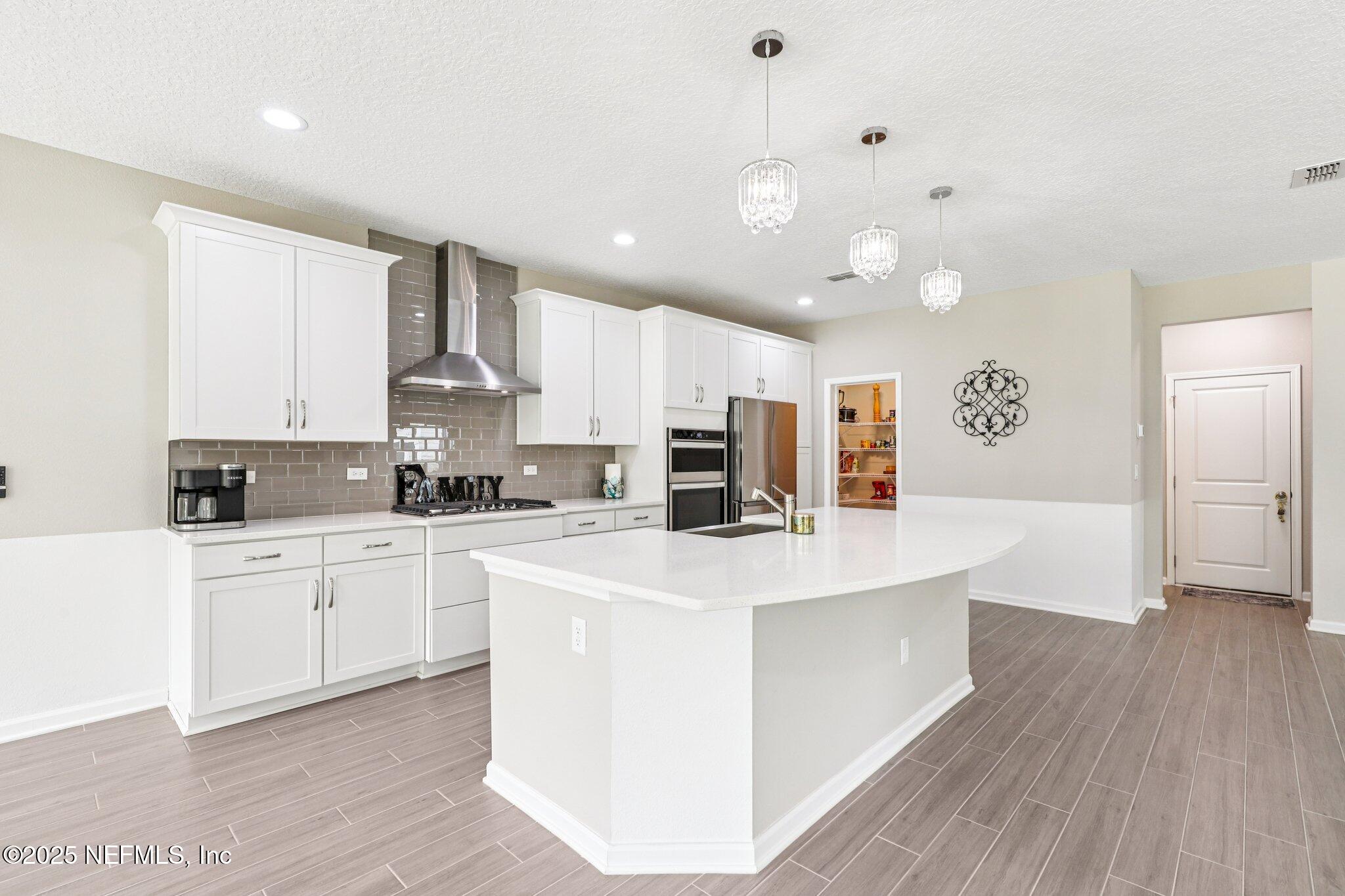 456 Stargaze Lane St. Augustine, FL 32095 - Photo 8 of 40 a large white kitchen with kitchen island a sink a center island stainless steel appliances and a cabinets