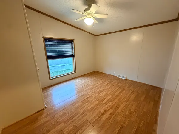 a view of an empty room with window and wooden floor