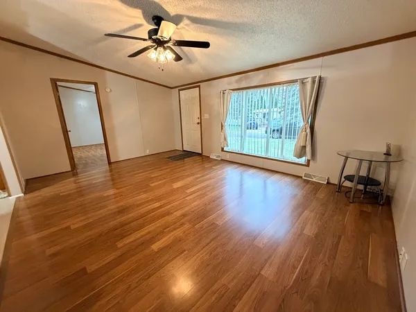 a view of empty room with wooden floor and fan
