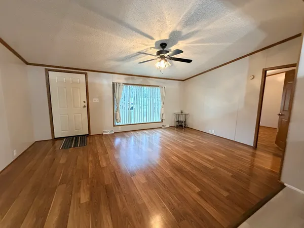 a view of empty room with wooden floor and fan