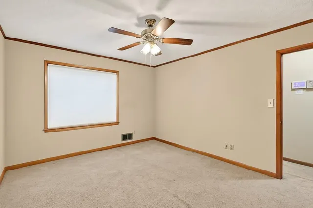 an empty room with window and ceiling fan