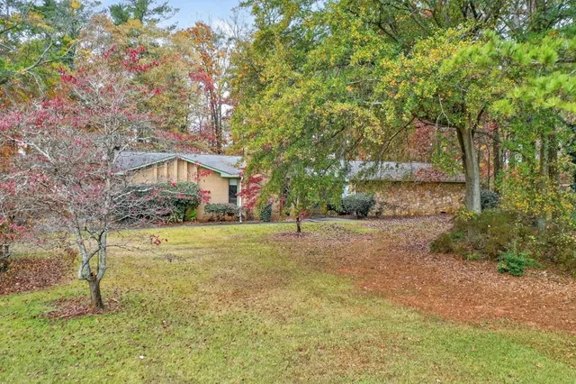 a front view of a house with a yard and a large tree