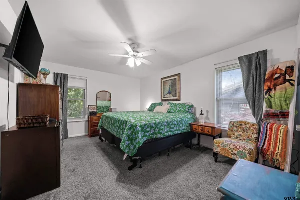 a bedroom with a bed a couch and a flat tv screen on the dresser