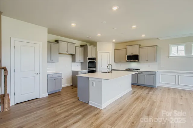 a large kitchen with a center island and a wooden floor