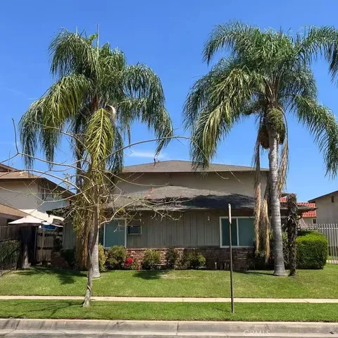 a view of a palm trees front of house with a yard