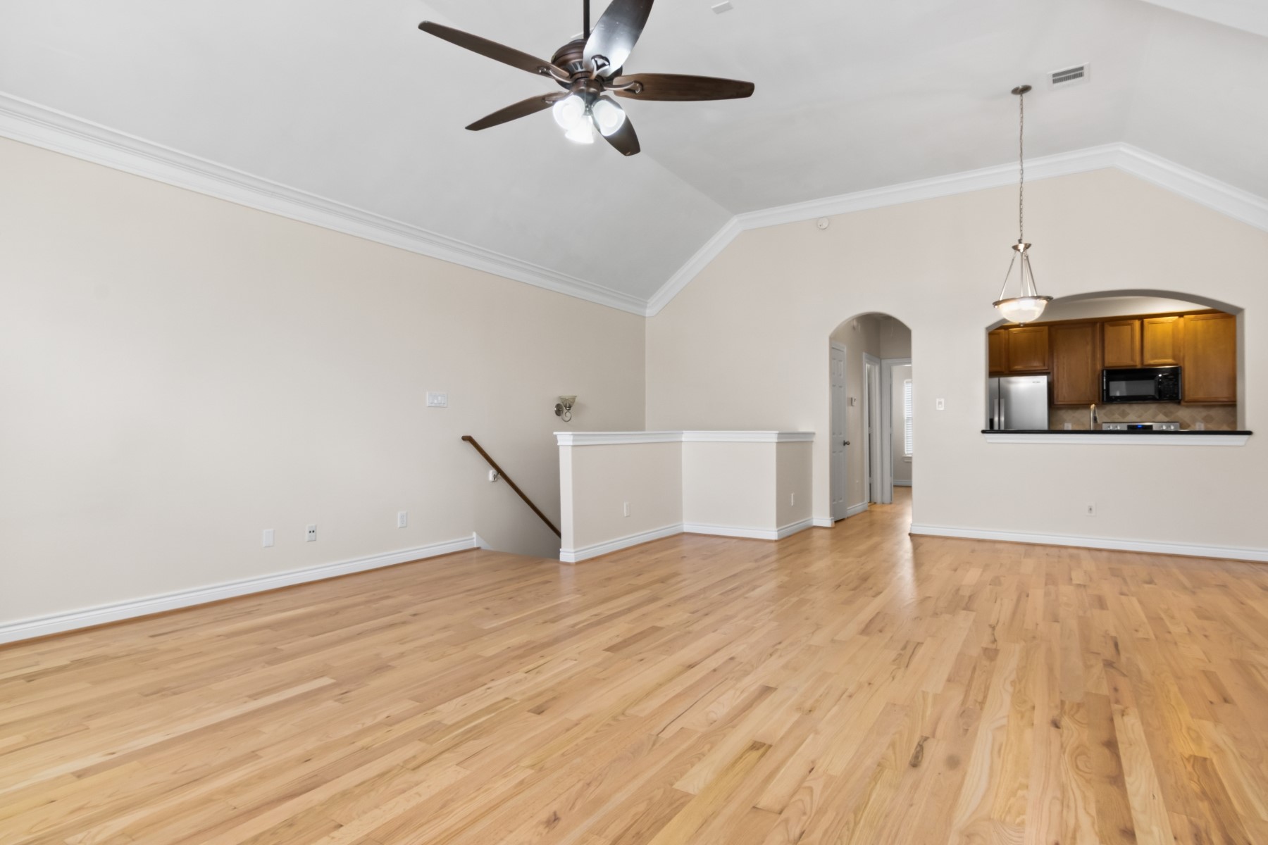 a view of empty room with wooden floor and ceiling fan