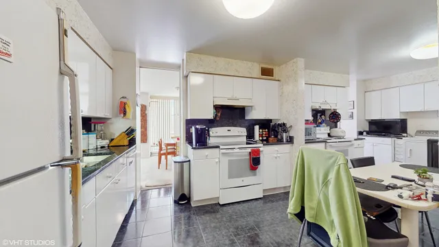 a kitchen with a refrigerator a stove and white cabinets with wooden floor