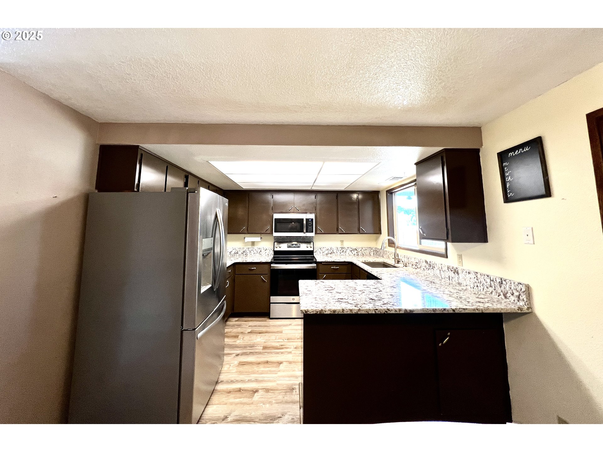554 67th Street Springfield, OR 97478 - Photo 8 of 32 a kitchen with stainless steel appliances kitchen island granite countertop a refrigerator and a sink
