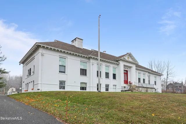 a view of a white house with a big yard and large trees