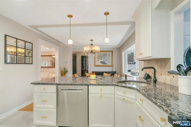 a kitchen with kitchen island granite countertop a stove a sink a refrigerator and white cabinets with wooden floor
