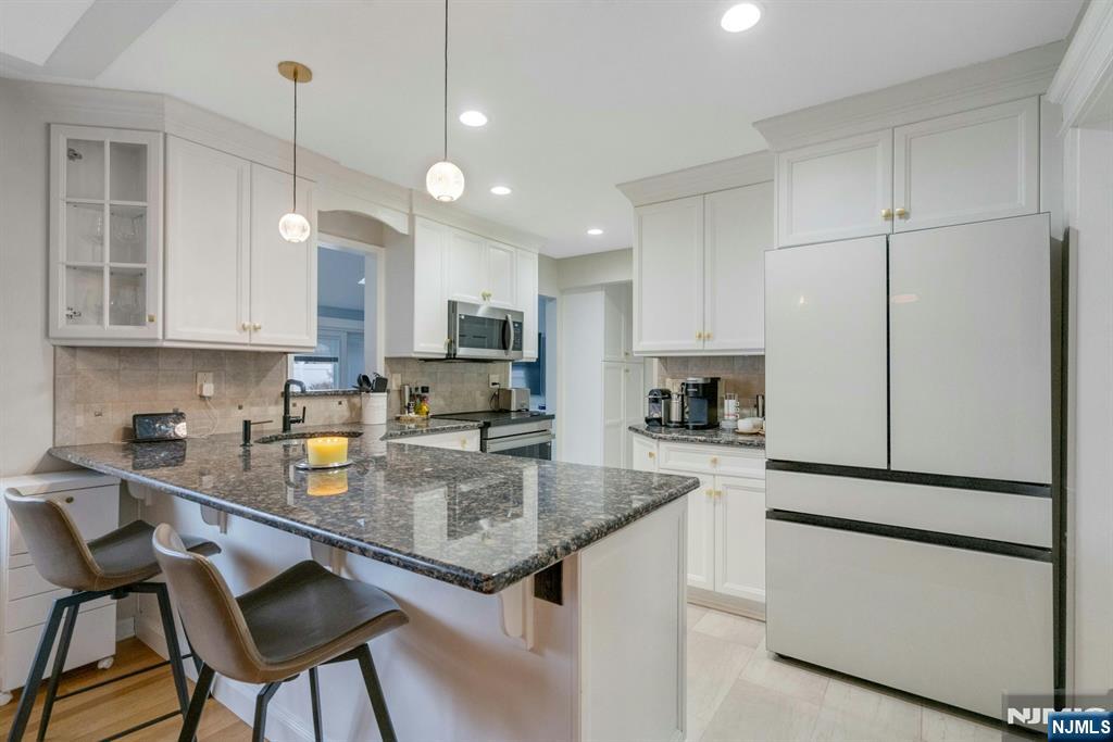 111 Crain Road Paramus, NJ 07652 - Photo 10 of 30 a kitchen with kitchen island granite countertop a stove a sink a refrigerator and white cabinets with wooden floor