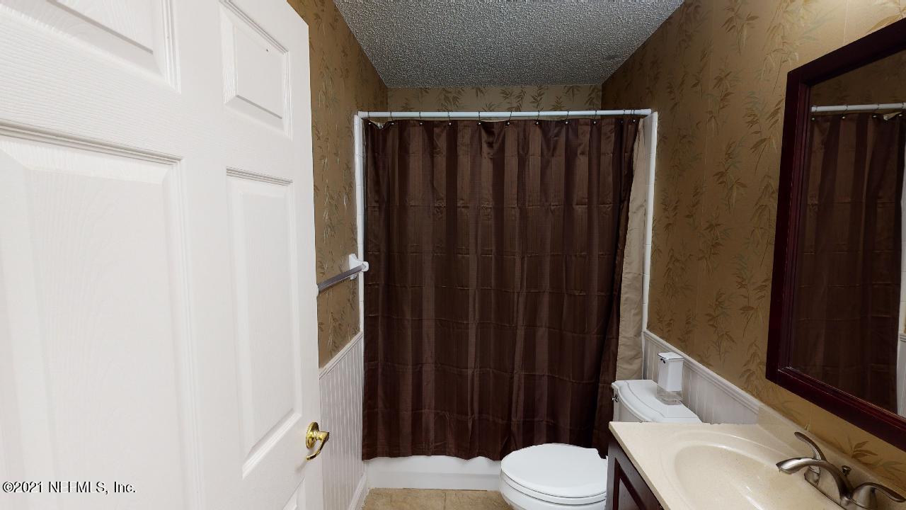 3130 Mountain Ash Road South Jacksonville, FL 32223 - Photo 37 of 60 a bathroom with a sink a toilet a mirror and shower curtain