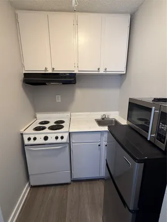 a kitchen with granite countertop a stove and a white cabinets