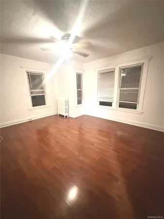 a view of an empty room with window and wooden floor