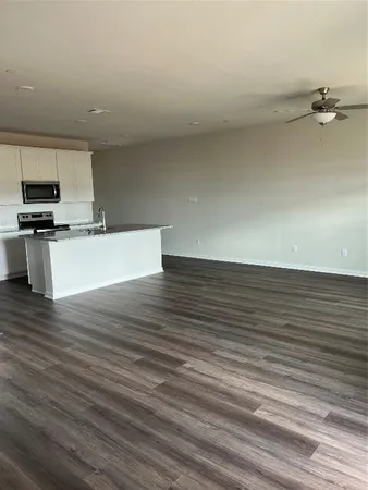 a view of kitchen and empty room with wooden floor
