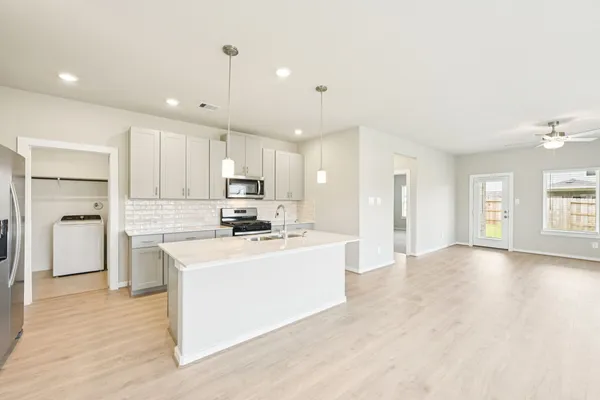 a kitchen with kitchen island a sink a stove a refrigerator cabinets and a window