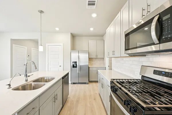 a kitchen with stainless steel appliances kitchen island granite countertop a sink and a refrigerator