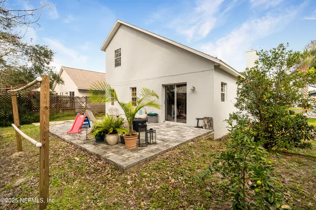 a view of a patio with table and chairs potted plants and floor to ceiling window