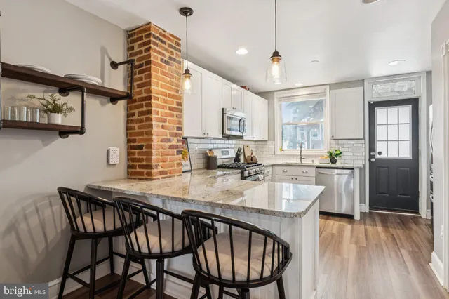 a kitchen with stainless steel appliances kitchen island granite countertop a stove top oven a sink dishwasher and a microwave oven with cabinets
