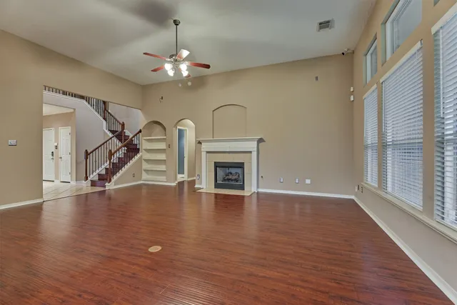 a view of an empty room with wooden floor fireplace and a window