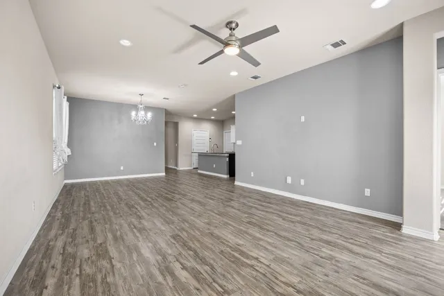 an empty room with wooden floor and a ceiling fan