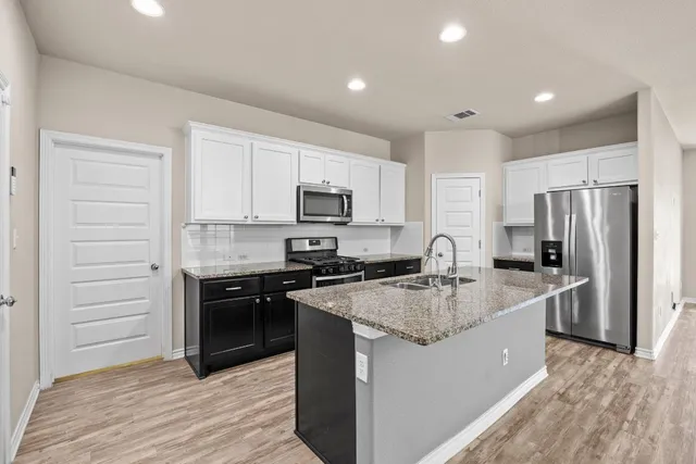 a kitchen with stainless steel appliances granite countertop a refrigerator a stove a sink and a microwave