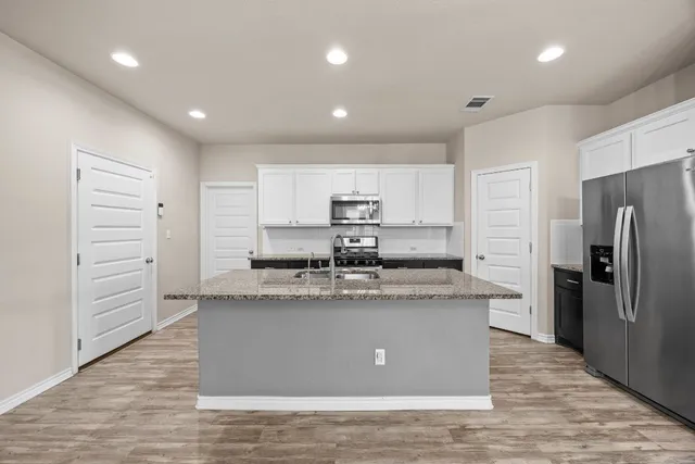 a large kitchen with stainless steel appliances granite countertop a large counter top and a stove top oven