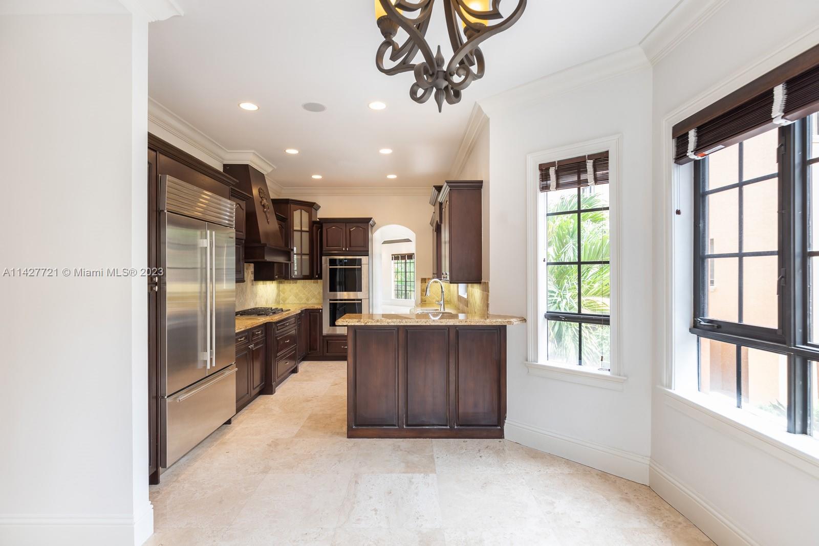 3471 Main Highway, Unit 928 Miami, FL 33133 - Photo 8 of 40 a kitchen with kitchen island wooden cabinets and refrigerator