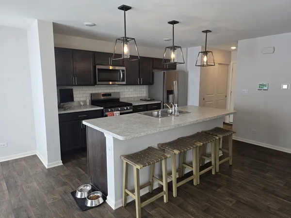 a kitchen with kitchen island granite countertop a sink appliances and wooden floor