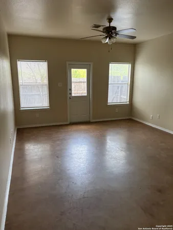 an empty room with windows and fan