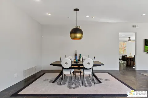 a dining room with stainless steel appliances furniture a rug and a kitchen view