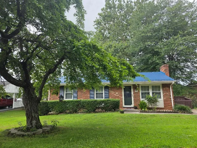 a kitchen with granite countertop white cabinets white appliances a sink and a window
