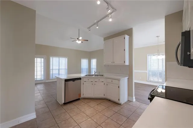 a large white kitchen with a window and refrigerator