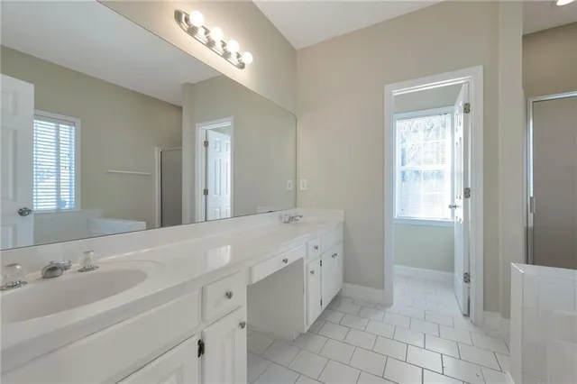 a spacious bathroom with a double vanity sink a mirror and a bathtub