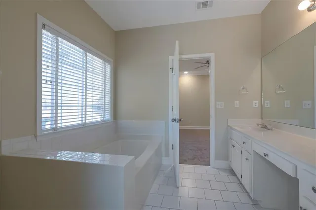 a spacious bathroom with a granite countertop sink a mirror and a bathtub