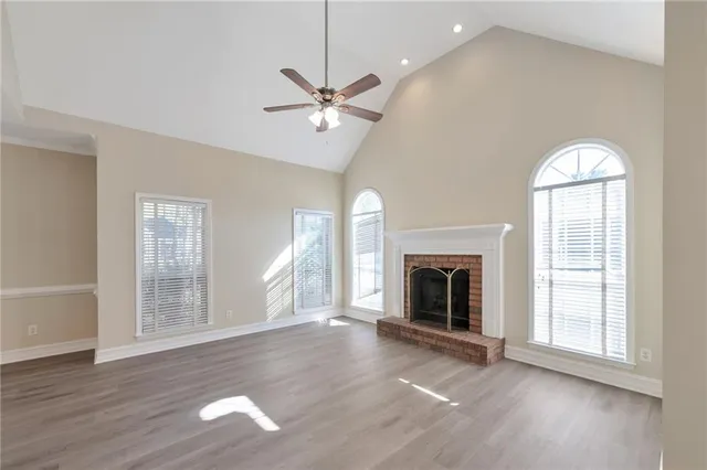 an empty room with wooden floor fireplace and windows