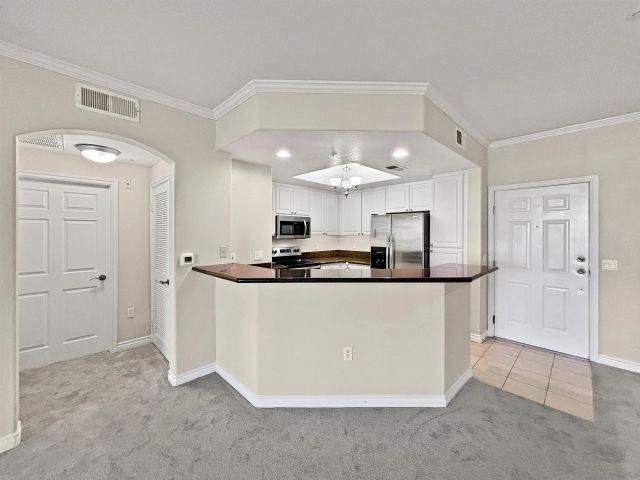 a view of kitchen with stainless steel appliances granite countertop a refrigerator a sink dishwasher and white cabinets with wooden floor