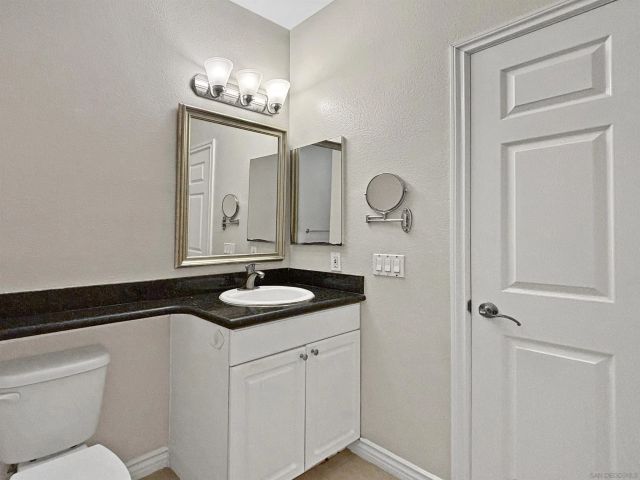 a bathroom with a granite countertop sink a toilet and a mirror