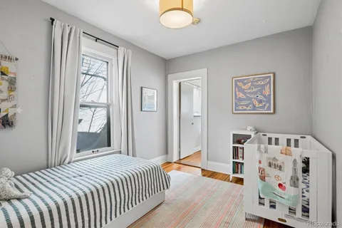 a bedroom with a bed and a window with wooden floor