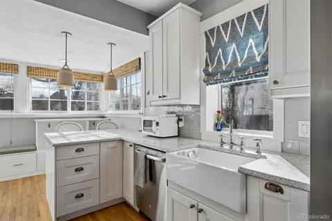 a view of a kitchen with stainless steel appliances granite countertop a sink and dishwasher with white cabinets