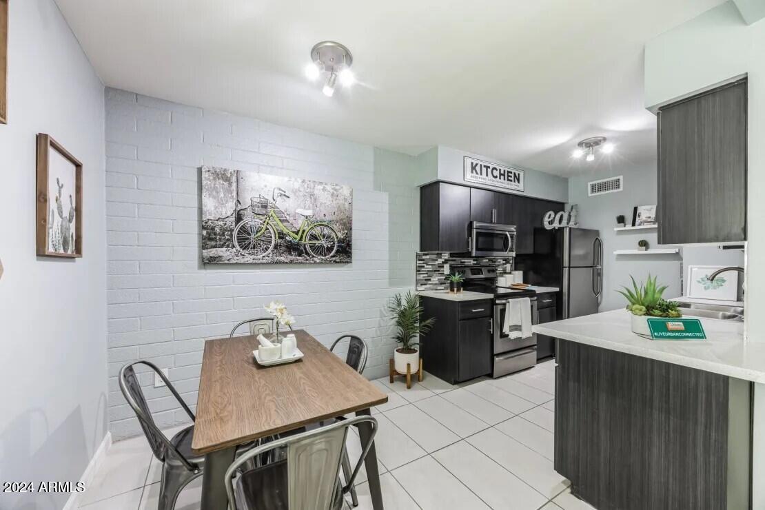 1220 North 44th Street, Unit 1 Phoenix, AZ 85008 - Photo 3 of 15 a kitchen with stainless steel appliances kitchen island granite countertop a stove a refrigerator a sink a dining table and chairs with wooden floor