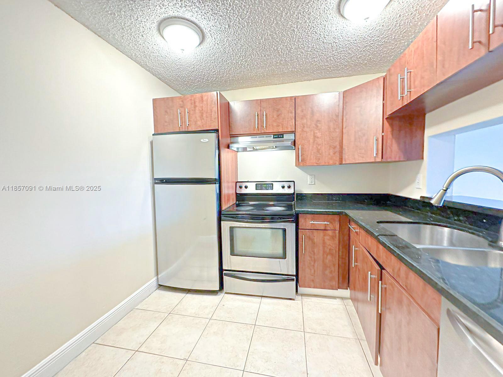 a kitchen with granite countertop a refrigerator and a sink