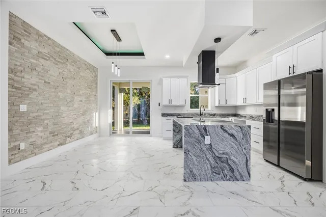 a kitchen with stainless steel appliances kitchen island granite countertop a refrigerator a stove and a sink