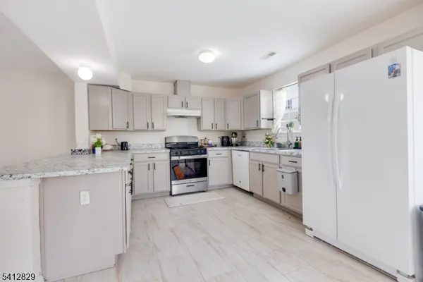 a kitchen with granite countertop white cabinets and white stainless steel appliances