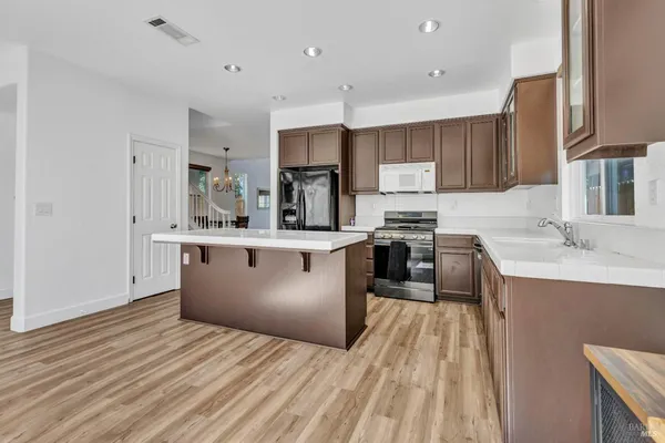 a kitchen with stainless steel appliances kitchen island granite countertop a sink stove and refrigerator